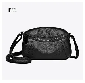 Close-up of black litchi grain leather texture and curved zipper on crossbody bag