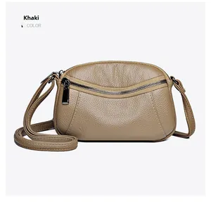 Close-up of khaki pebbled leather crossbody bag with front zipper pocket and strap
