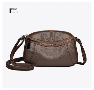 Close-up of brown crossbody bag featuring pebble leather texture and curved zipper pocket