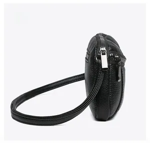 Side view of black lychee grain leather crossbody bag featuring silver metal zippers