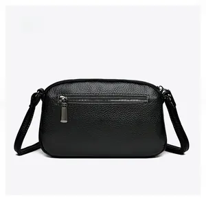 Detail view of the back of a black pebble leather crossbody bag with metal zipper pocket