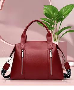 Detail view of large red tote bag with dual zippers and geometric pattern strap