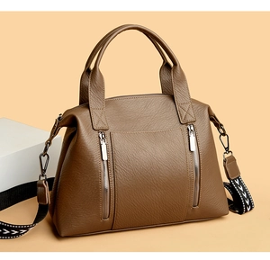 Detail of brown faux leather tote bag with dual front zippers and patterned strap