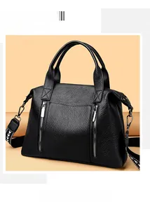 Close-up of black pebbled leather tote bag featuring decorative zippers and geometric strap