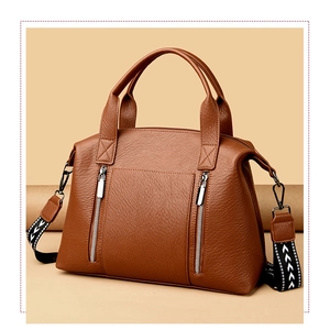 Detail of brown litchi leather tote with functional zippers and geometric patterned strap