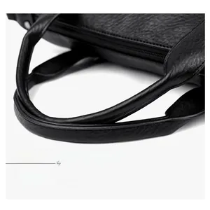 Detailed macro view of black lychee leather tote bag handles and secure zipper closure