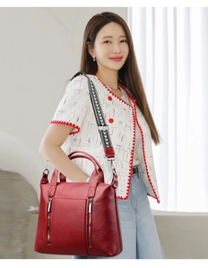 Detail of red pebbled leather tote bag with wide arrow pattern woven shoulder strap