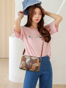 Detail of crossbody bag with geometric block patterns and textured brown leather strap