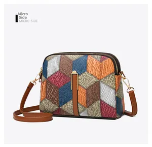 Detail view showing dual gold zippers and multi-color patchwork leather on the crossbody bag