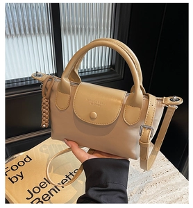 Detail of cream leather handbag with embossed lettering and woven rope charm