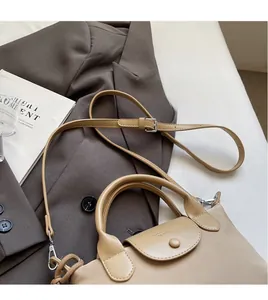Detail of khaki leather satchel with smooth shoulder strap on brown blazer backdrop