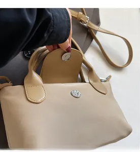 Detail of the strong magnetic buckle closure on a beige nylon crossbody dumpling bag