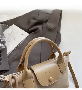 Detailed view of beige nylon handbag with leather handle and fashion logo engraving