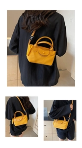 Detail of yellow nylon crossbody bag featuring woven rope charm and dual top handles