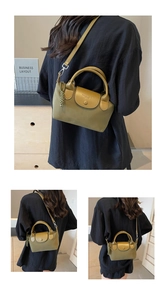Detail of olive green nylon handbag with adjustable strap and woven side ornament