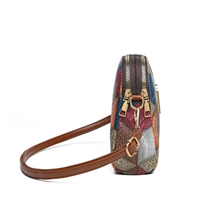 Multicolor patchwork crossbody bag with dual zippers and golden hardware on white background