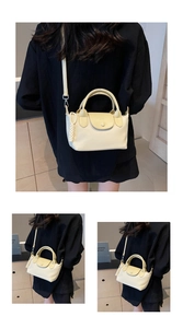 Detail of cream nylon mini handbag featuring woven rope charm and detachable strap