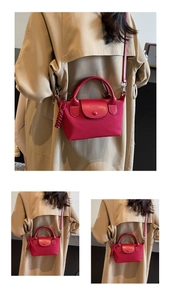 Detail of red nylon tote with leather flap and woven tassel charm on adjustable strap