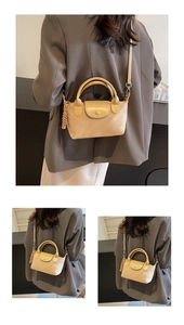 Close-up of a beige crossbody bag featuring a soft leather texture and woven charm detail