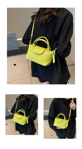 Detail view of bright yellow leather handbag with adjustable strap and woven pendant charm
