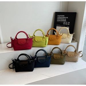 Detail view of colorful mini nylon crossbody bags with leather flap and woven charms