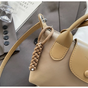 Close-up of beige nylon crossbody bag with braided rope charm and fashion logo
