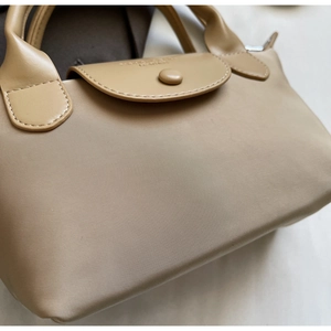 Detailed macro view of beige nylon fabric with leather flap and embossed metal snap button