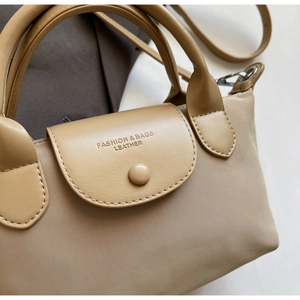 Detailed top view of nylon handbag showing leather flap with metal snap button closure