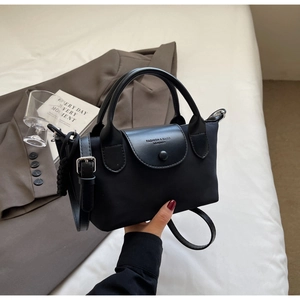 Close-up of black nylon handbag featuring leather flap with Fashion & Bags logo engraving