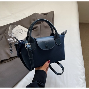 Close-up of navy nylon crossbody bag with black leather flap and fashion logo detail