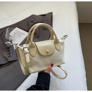 Detail of cream nylon handbag showing adjustable leather strap and top handle