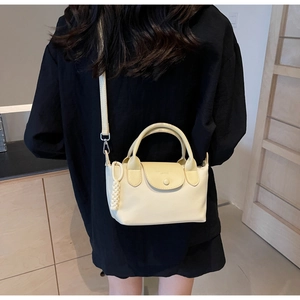 Detail of a beige nylon crossbody bag featuring a soft dumpling shape and braided charm