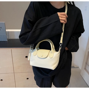 Detailed view of an off-white nylon crossbody bag with leather flap on a casual outfit