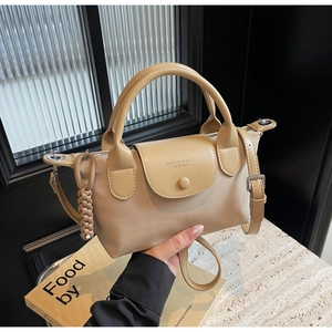 Detail of beige nylon mini handbag featuring leather handles and woven rope pendant