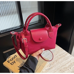 Detail of red nylon handbag with leather flap held by a model in a minimalist setting