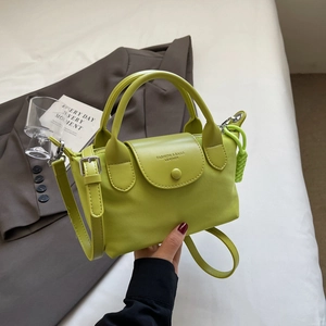 Lime green nylon crossbody bag with top handles on a gray blazer and white bedspread