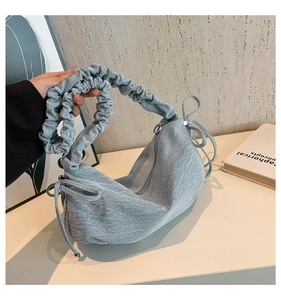 Λεπτομέρεια από γαλάζια τσάντα denim με σούρες στη λαβή και διακοσμητικούς φιόγκους