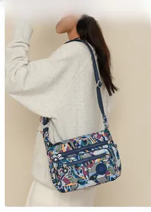 Detail view of multi-pocket navy crossbody bag with geometric print and nylon strap