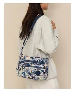 Detail of floral nylon crossbody bag featuring multiple zipper compartments and adjustable strap