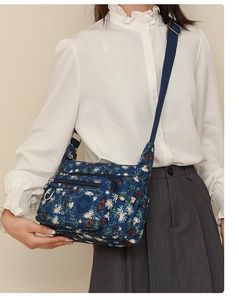Detail view of floral Oxford fabric crossbody bag showing zippers and waterproof texture