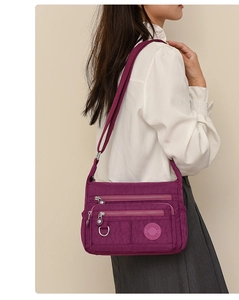 Detail of waterproof oxford multi-pocket crossbody bag in mulberry color worn by model