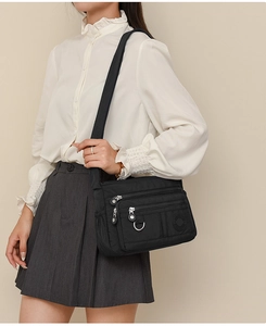 Detail of water-resistant black oxford cross-body bag featuring multiple zipper pockets