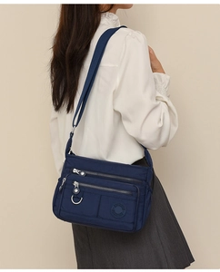 Detailed side view of navy blue multi-compartment crossbody bag in water-resistant nylon