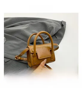 Detail view of mini caramel leather handbag with wrinkled texture and magnetic flap closure