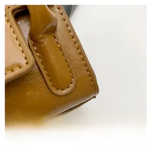Macro shot of premium brown glossy leather material and fine stitching on small square bag