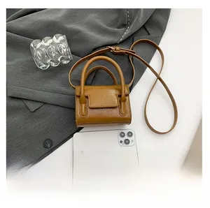 Caramel mini crossbody bag size comparison with smartphone on grey fabric background