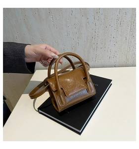 Détail d'un mini sac à main marron caramel avec texture plissée et anses rondes chic