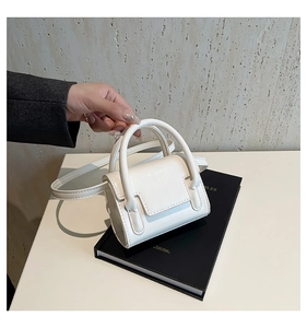 Détail du mini sac carré blanc minimaliste avec texture cuir et poignée supérieure