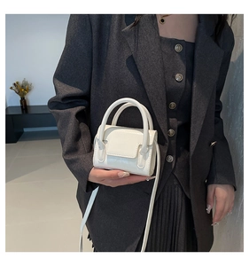 Mini sac à main carré crème en cuir verni brillant porté avec une veste blazer grise