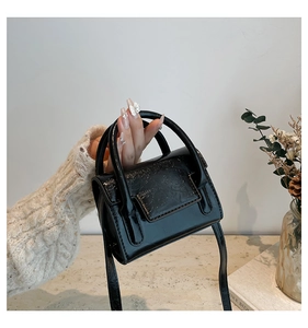 Détail d'un mini sac à main noir plissé brillant avec texture lisse et fine bandoulière